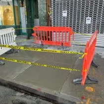 Storefront sidewalk pour protected by orange barricades